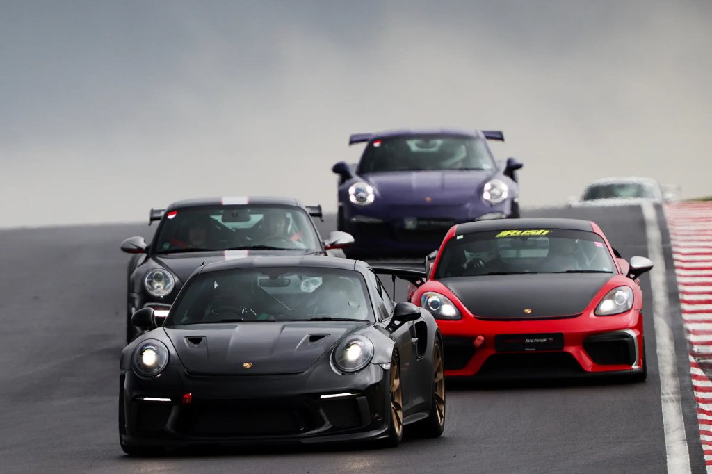 Porsche sports cars driving in a group on a circuit during a track day