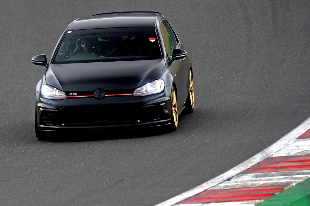 Black hatchback on circuit, its headlights on, during a track day