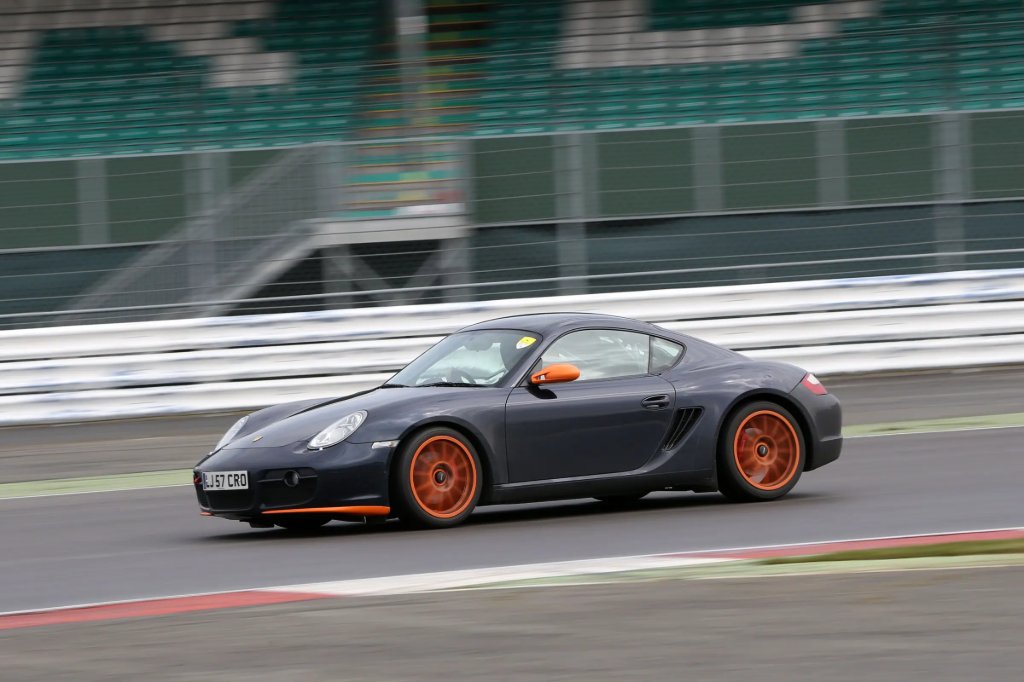 Grey Porsche Cayman with orange wheels on circuit during a track day